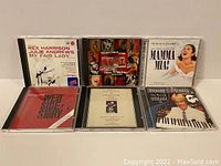 Front view of all six CD jewel cases, showing the cover art for each soundtrack including My Fair Lady, Rent, Mamma Mia, West Side Story, The Phantom of the Opera, and The Best of Andrew Lloyd Webber by Richard Clayderman.
