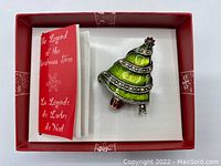 Top view of boxed Christmas tree brooch with small leaflet about the legend of the Christmas tree inside a red box