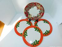 Plate with crimson wreath holiday pattern displayed on a stand, surrounded by four red border holly motif trivets.