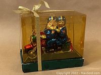 Ornament in original display box with gold ribbon, showing full packaging and presentation.