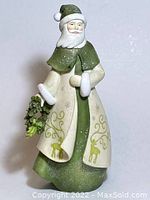 Full view of Santa figurine showing green and cream cloak with reindeer design, holding wreath.
