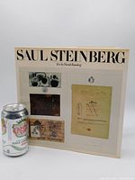 Front cover of the Saul Steinberg art book showing multiple images and artist's handwriting with a soda can for scale.