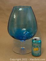 Large blue tinted glass snifter balloon shape shown next to a soda can for scale, standing approximately 13 inches tall.