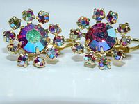 Close-up photo showing front view of the two aurora borealis rhinestone clip-on earrings featuring a central large crystal surrounded by smaller crystals in prong settings on gold-tone metal.