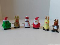 Six Christmas themed wind-up toys arranged in a single row, displayed against a plain background.