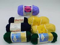 Seven balls of yarn in four colours: navy blue, yellow, green wool yarns, and lilac nylon yarn.
