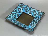 Blue stained glass candle holder shown from a top-side angle highlighting braided pattern and bead edge.