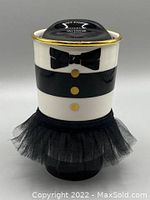Front view of ceramic mug showing black and white stripes, gold rim, black bowtie, three gold buttons, black mesh tutu base, and black press-in lid.