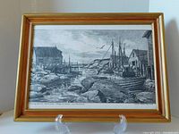 Full view of the framed black and white Lloyd Harding print showing maritime fishing village scene and wooden frame with gold edges.