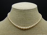 Single-strand pearl necklace displayed on fabric bust, full view