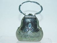 Front view of vintage Victorian purse ornament showing detailed lattice pattern, marquise glass stone centerpiece, and glittery silver bottom half with beaded handle.