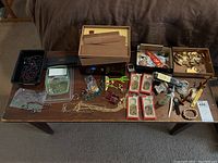Overview of lot including jewelry box, watches, pins, necklaces, and cigar box on a table