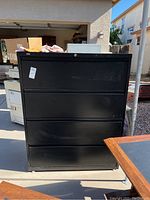 Front view of the black metal filing cabinet showing four drawers and lock mechanism on top drawer, no key included.