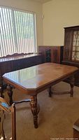 Full view of rectangular wood grain antique dining table in room with other furniture.