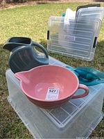 Large pink measuring bowl, ceramic, with handle and pouring spout, placed on plastic container outdoors