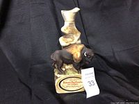 Front-facing view of the full ceramic decanter with buffalo figure and label attached.
