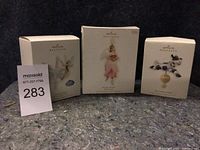 Three boxed Hallmark Keepsake ornaments including a fairy, angel, and blue jays bell.