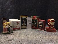 Photo of six Christmas ornaments including three boxed Hallmark Keepsakes and three other figurines: Santa Claus holding a bag, teddy bears in wedding attire, and a snowman figurine.