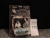 Front view of the Hot Wheels Legends Hall of Fame Corvette die-cast car in sealed blister packaging, showing a blue Corvette model and image of Vic Edelbrock on the card.