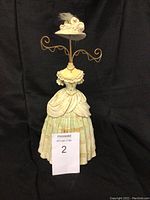 Front view of the vintage lady dress jewelry holder with wire hooks featuring pastel colors and feathered hat.