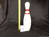 Full view of white bowling pin shaped decanter with red stripes and a ruler beside it for size reference.