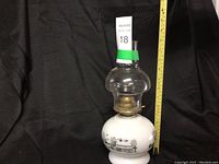 Large oil lamp on black background with measuring tape showing height, tag marked masold 18.