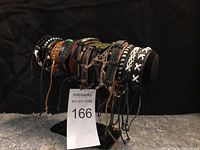 Front-side view of multiple leather bracelets arranged on a black holder, showing various designs and colors.