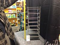 Clear acrylic spinning jewelry holder with multiple angled tiers and black base shown with measuring tape for size reference.