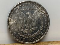 Reverse side of 1882 American silver dollar coin showing eagle with wings spread, clutching arrows and olive branch, surrounded by wreath and inscriptions.