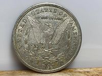 Reverse side of 1921 American Silver Morgan Dollar showing eagle holding arrows and olive branches with inscriptions.