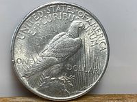 Reverse side of the 1922 American Silver Peace Dollar showing a perched eagle clutching an olive branch with radiant lines and text 'UNITED STATES OF AMERICA', 'E PLURIBUS UNUM', and 'ONE DOLLAR'. The coin shows surface wear and minor scratches.