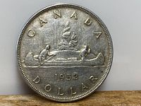 Reverse side of the 1952 Canadian silver dollar showing the iconic voyageur canoe scene with northern lights.
