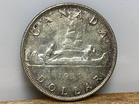 Reverse side of 1954 Canadian silver dollar coin showing Voyageur design with canoe, 'CANADA DOLLAR' text and year.