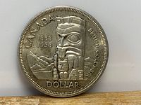 Obverse side of the 1958 Canadian silver dollar coin showing a Northwest Coast Indigenous totem pole with inscriptions.