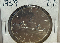 Obverse side of the 1959 Canadian silver dollar coin showing the canoe design with two paddlers, the word 'CANADA', the denomination 'DOLLAR', and the year '1959'.