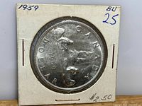 Photo showing the reverse side of the 1959 Canadian silver dollar coin with the canoe design and denomination.