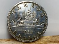 Obverse side of a 1963 Canadian silver dollar coin showing the canoe design with the inscription 'CANADA DOLLAR 1963'.