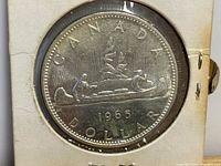 Side showing two men paddling a canoe and stylized trees with sunrays, year 1965, and inscriptions CANADA DOLLAR.