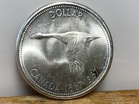 Obverse side of the Canadian Silver Dollar featuring flying goose design and date range 1867-1967.
