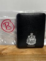 Black leather-like presentation case with Canadian coat of arms and 'Canada' text.