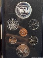 Coins displayed in original black holder panel showing front faces, including Winnipeg Centennial 100 Canada Dollar, 25 cents, 10 cents, and 5 cents coins from 1974.