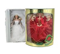 Blushing Bride Barbie doll in white gown and veil next to Happy Holidays Barbie doll in red dress inside original packaging, showing condition and wear on boxes.