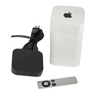 White Apple TV device next to black power adapter and silver Apple remote control, showing top and side views of items.