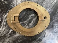 Top-down view of brass porthole frame showing hinged circular opening and mounting holes