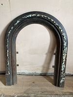 Full front view of arched cast iron surround on floor against wall