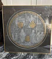 Full view of large circular rubbing framed under glass showing human figures and heraldic shields with gold accents.