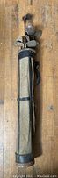 Canvas golf bag containing several vintage wooden shaft golf clubs on wooden floor