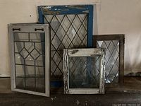 Full set of four vintage leaded glass windows arranged small to large, showing distressed paint and diamond glass patterns.