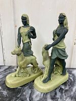 Side and front view of male and female vintage chalkware figures with dogs on bases showing condition and style