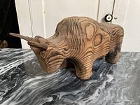 Front and left side view of large wooden bull sculpture showing wood grain patterns and stylized shape.